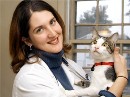 Bio photo of Dr. Stephanie Janeczko, smiling in a white lab coat holding a gray and white cat