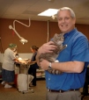 Bio photo of Rick DuCharme, in a blue shirt, smiling and holding a brown cat
