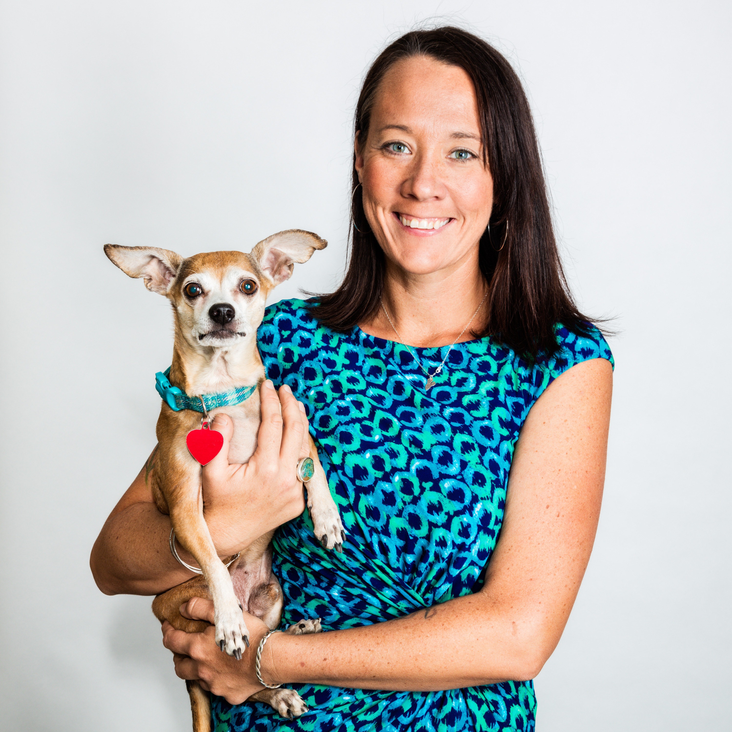 Bio photo of Kristen Auerbach, smiling in a patterned shirt as she holds a chihuahua