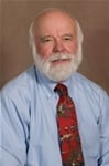 Bio photo of Dr. Ronald Schultz, smiling in a light blue dress shirt and colorful tie