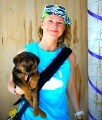 Bio photo of Dr. Katherine Polak smiling in a blue shirt, holding a brown and black dog