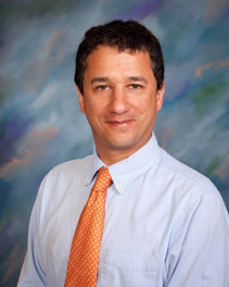 Bio photo of Dr. Santiago Peralta, smiling in a pale dress shirt with an orange tie