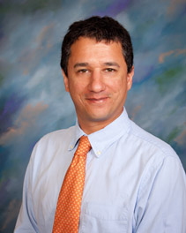 Bio photo of Dr. Santiago Peralta, smiling in a pale dress shirt with an orange tie