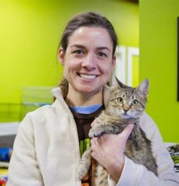 Bio photo of Ellen Jefferson, smiling and holding a black and brown cat