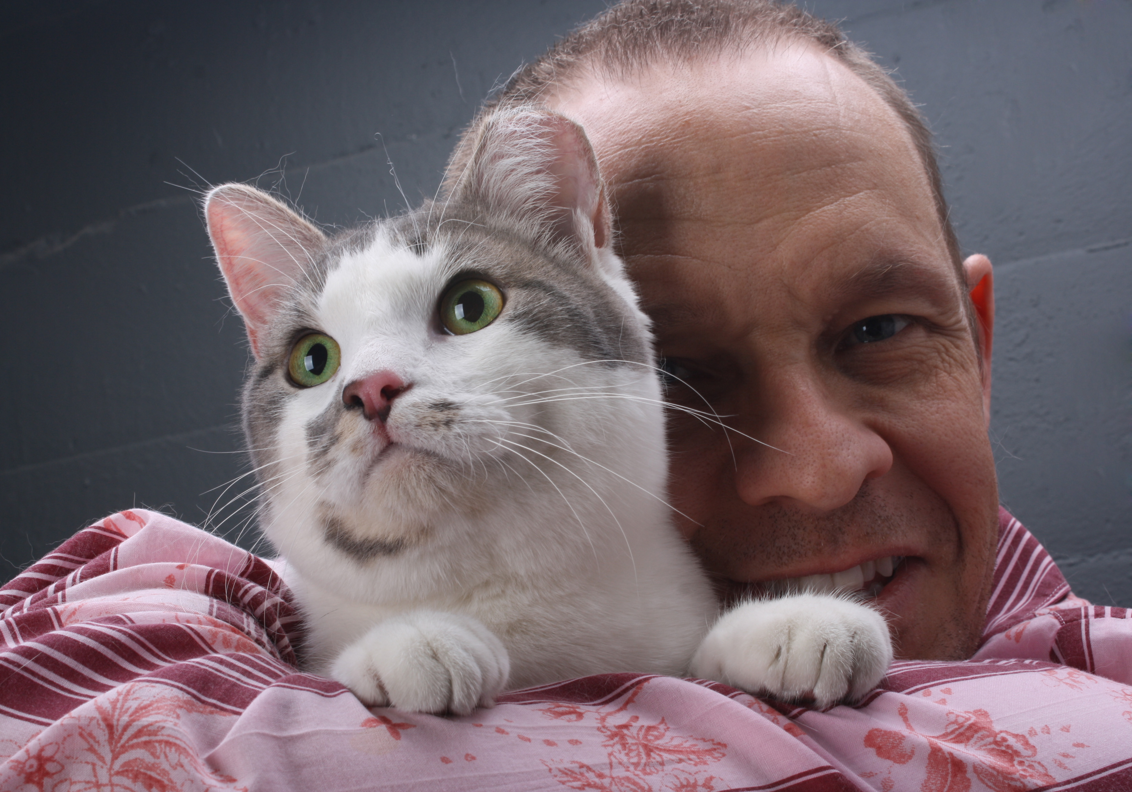 Bio shot of Peter J. Wolf, smiling and hugging a gray and white cat