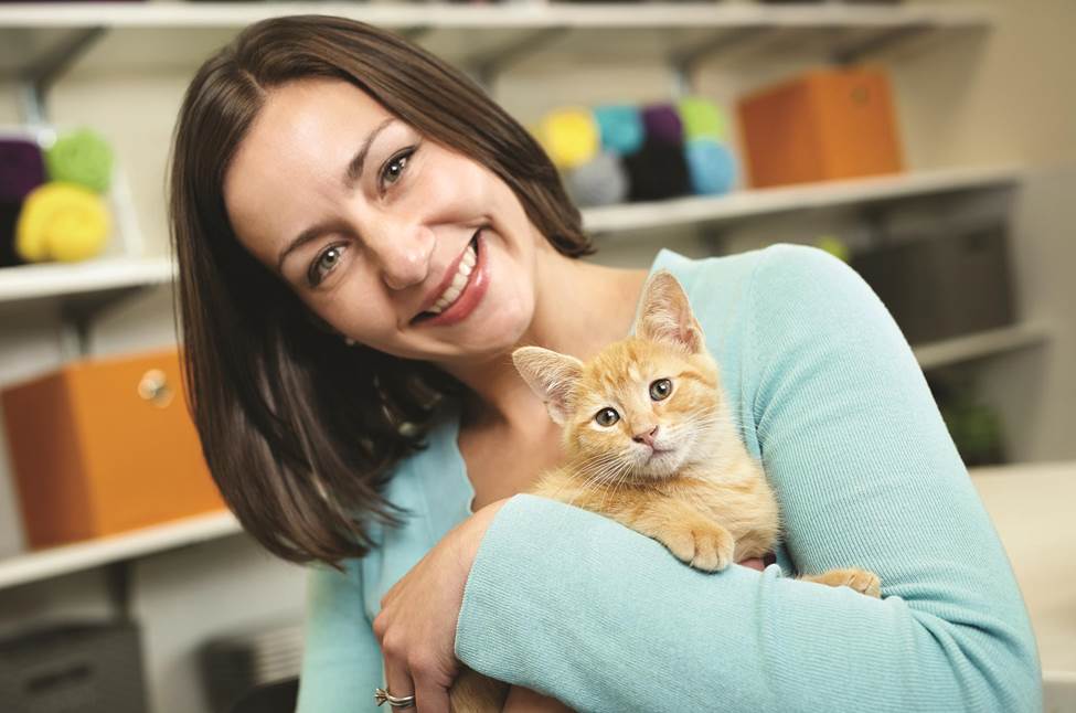 Photo of Rachel D. K. Finney smiliing in a pale green shirt holding a little orange cat