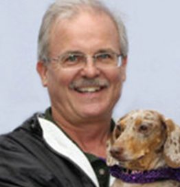 Bio photo of Rob Goddard smiling and holding a dachshund dog