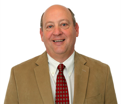Bio photo of Wiley Stem, III, smiling in a tan coat, over a white shirt with a red-patterned tie