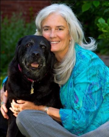 Bio photo of Diane Blankenburg smiling next to a black dog