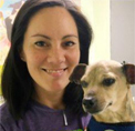 Bio photo of Jordana Moerbe, smiling in dark hoodie, with a small white dog