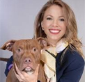 Bio photo of Laura Donahue, smiling with a brown dog, against a light background