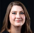 Bio portrait of Nikki Reck, smiling in front of a dark background