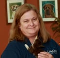 Bio photo of Rebecca Guinn, smiling in a dark blue shirt, holding a black and white cat