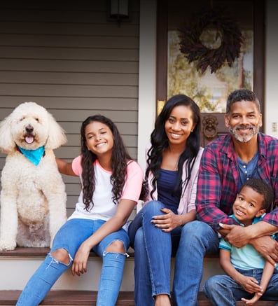 Young happy family with two children sitting on a porch with a large white dog