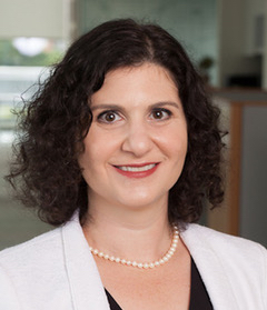 Bio photo of Abby Volin, smiling in a white coat