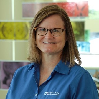 Bio photo of Dr. Julie Levy, smiling in a blue shirt in an indoor setting