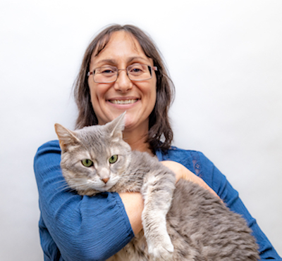 Bio photo of Dr. Linda Jacobson, smiling in a blue shirt against a white background, holding a gray and white cat
