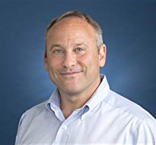 Bio photo of Dr. Steven G. Rogelberg, smiling in a pale blue dress shirt