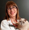 Bio photo of Dr. Annette Litster in a white lab coat, smiling and holding a white cat