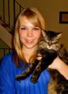 Bio photo of Dr. Danielle Boes, smiling in a blue dress, holding a brown and black cat