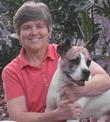 Bio photo of Dr. Cynda Crawford in a peach-colored shirt, smiling and holding brown and white dog