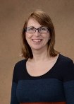 Bio photo of Dr. Annette Litster, smiling in a dark shirt against a tab background