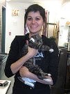 Bio photo of Jesse Oldham smiling in a dark coat holding a black and gray cat