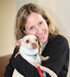 Bio photo of Dr. Laurie Peek in a black sweater hugging a white dog