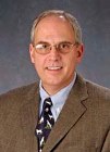 Bio photo of Dr. Robert Weedon smiling in a brown suit and tie