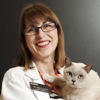 Bio photo of Dr. Annette Litster in a white lab coat, smiling and holding a white cat